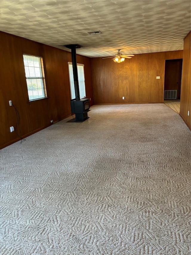 145 Timberline Dr, Whitney, TX 76692 - carpeted spare room with a wood stove, ceiling fan, and wooden walls