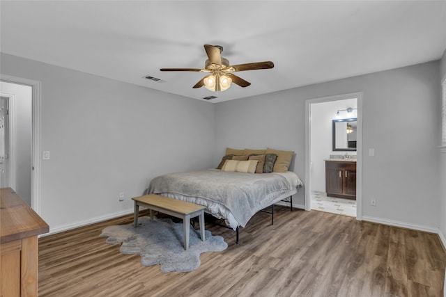 bedroom with connected bathroom, wood finished floors, visible vents, and baseboards