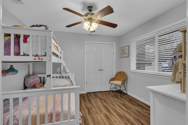 bedroom with a closet, visible vents, a ceiling fan, wood finished floors, and baseboards