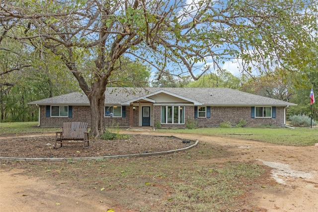 ranch-style home with a shingled roof, brick siding, and a front lawn