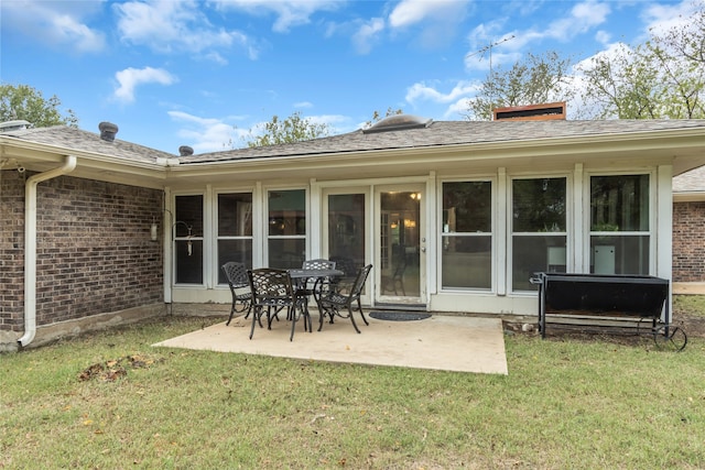 rear view of house featuring a patio area, roof with shingles, a yard, and brick siding