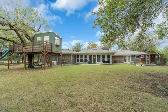 rear view of property with brick siding, a lawn, and stairway