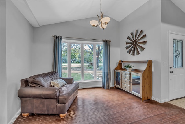 living area featuring a chandelier, lofted ceiling, baseboards, and wood finished floors