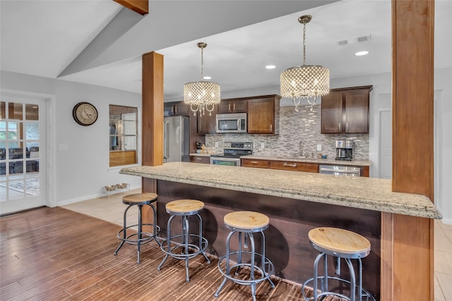 kitchen with visible vents, stainless steel appliances, a breakfast bar area, and pendant lighting