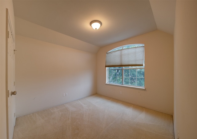 spare room with light carpet and vaulted ceiling