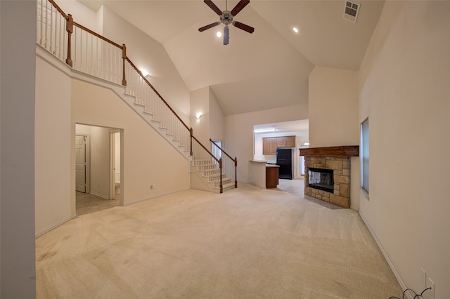 unfurnished living room with high vaulted ceiling, light colored carpet, ceiling fan, and a fireplace