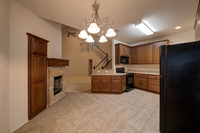 kitchen with black appliances, kitchen peninsula, ceiling fan with notable chandelier, a fireplace, and pendant lighting