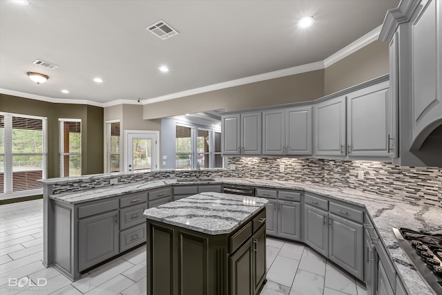 kitchen featuring gray cabinetry, ornamental molding, a kitchen island, decorative backsplash, and stainless steel gas stovetop