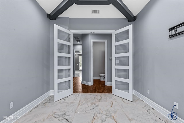 unfurnished bedroom featuring lofted ceiling with beams, light hardwood / wood-style floors, and french doors