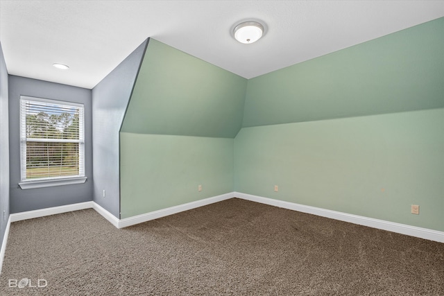 additional living space featuring carpet flooring and vaulted ceiling