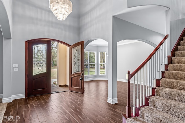 entryway featuring dark wood-type flooring, a high ceiling, and a notable chandelier