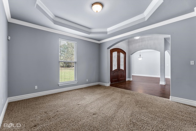 carpeted entryway featuring an inviting chandelier, ornamental molding, and a raised ceiling