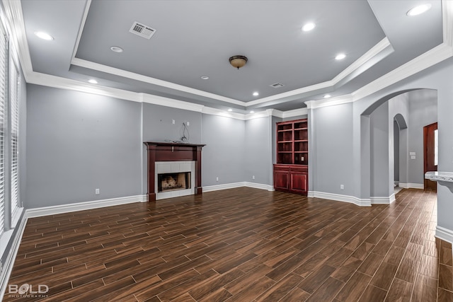 unfurnished living room featuring ornamental molding, a tile fireplace, dark hardwood / wood-style floors, and a raised ceiling