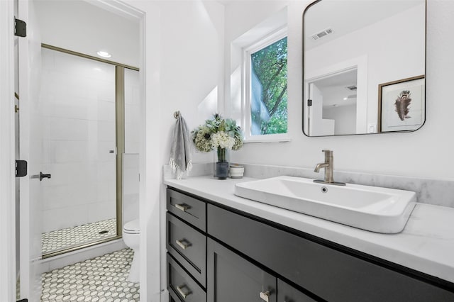 bathroom featuring tile patterned floors, vanity, a shower with shower door, and toilet