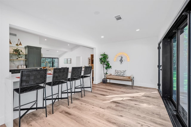 kitchen featuring a kitchen bar, sink, light hardwood / wood-style flooring, and green cabinetry