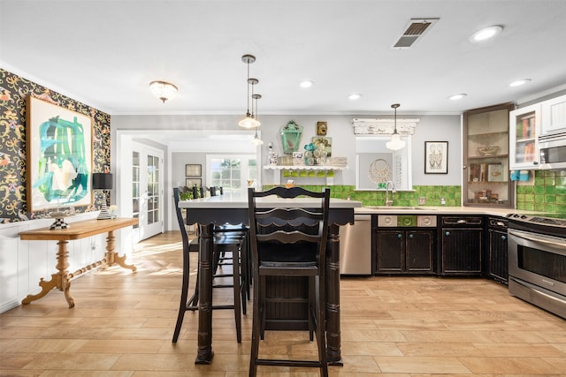 kitchen with stainless steel appliances, backsplash, pendant lighting, sink, and a breakfast bar