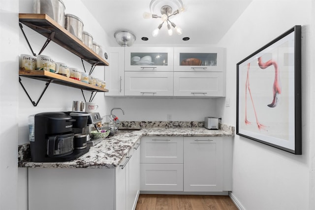 7117 Serrano Dr, Benbrook, TX 76126 - kitchen featuring open shelves, light wood-type flooring, white cabinetry, glass insert cabinets, and light stone countertops
