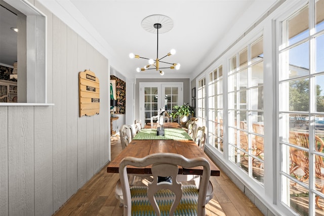 sunroom / solarium featuring a healthy amount of sunlight, an inviting chandelier, and french doors