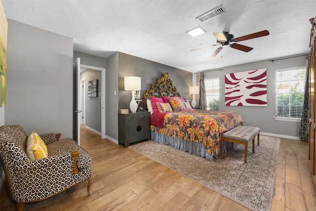 bedroom with hardwood / wood-style flooring, ceiling fan, and multiple windows