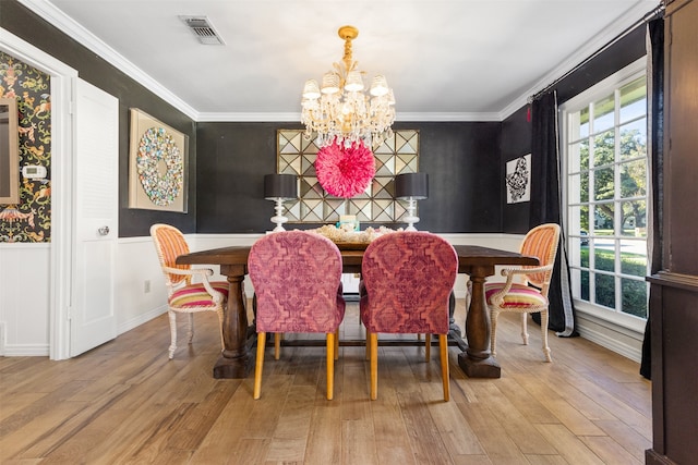 dining area with light wood-type flooring, a chandelier, and ornamental molding