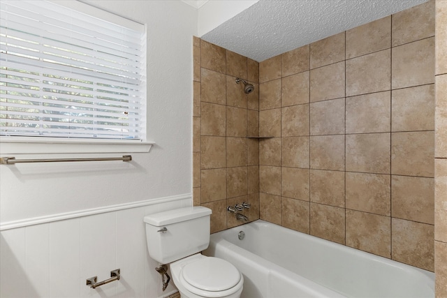 bathroom featuring toilet, tiled shower / bath, and a textured ceiling