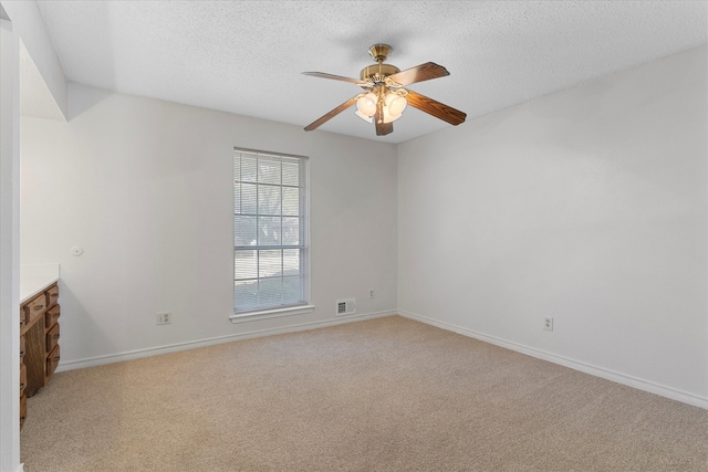 unfurnished room with ceiling fan, a textured ceiling, and light colored carpet