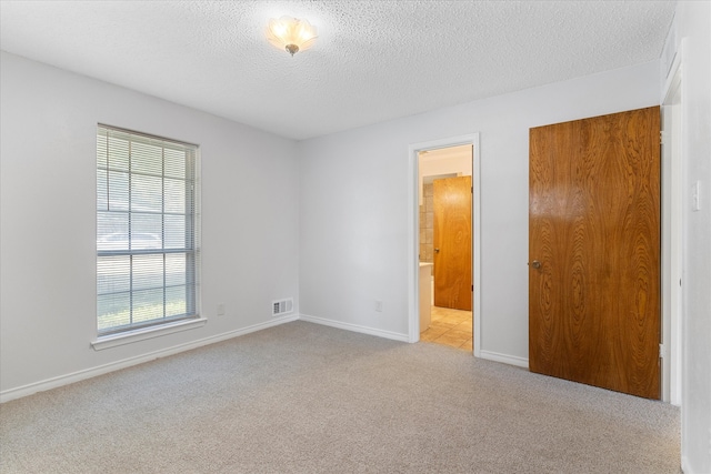 carpeted empty room featuring a wealth of natural light and a textured ceiling