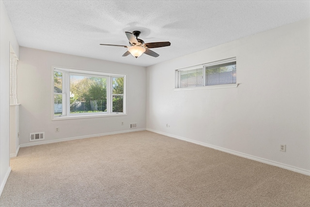 carpeted spare room featuring a textured ceiling and ceiling fan