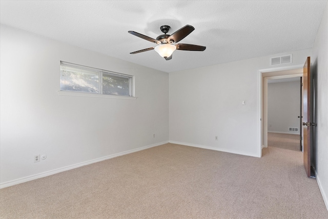 empty room featuring ceiling fan, a textured ceiling, and light carpet