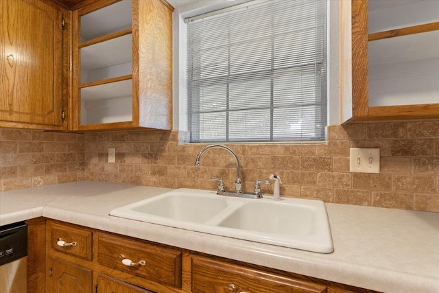 kitchen featuring stainless steel dishwasher, sink, and backsplash