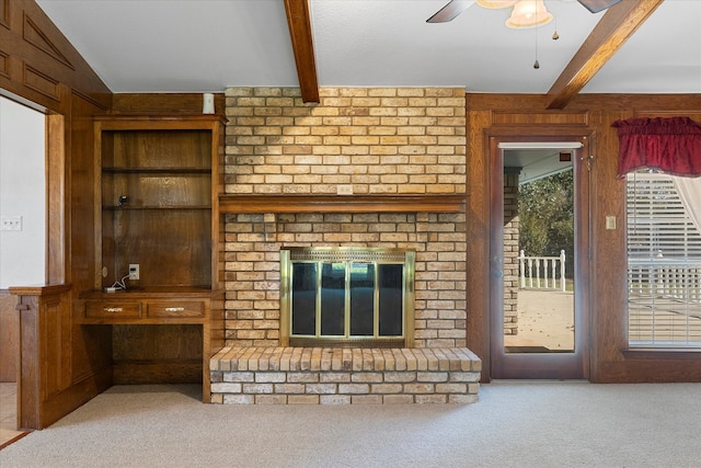 unfurnished living room featuring a brick fireplace, wood walls, light carpet, and beam ceiling