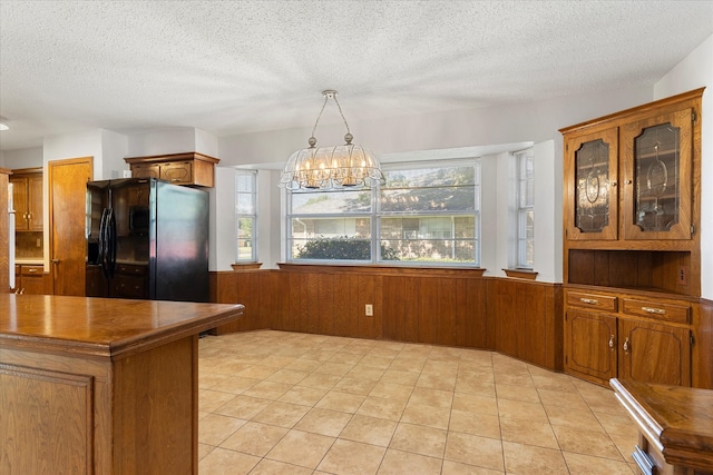 kitchen with hanging light fixtures, a textured ceiling, black fridge with ice dispenser, and plenty of natural light