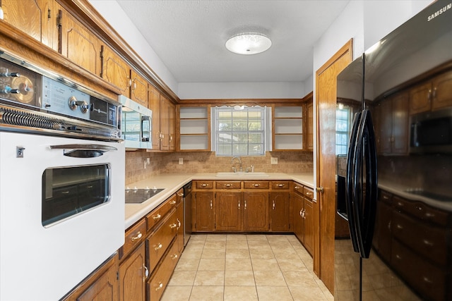 kitchen featuring stainless steel appliances, light tile patterned floors, sink, and decorative backsplash