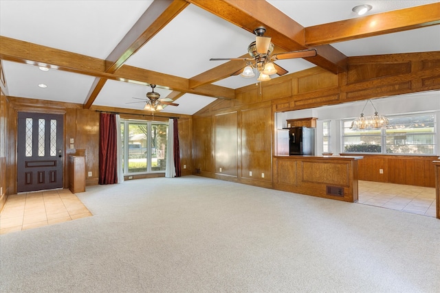 unfurnished living room with lofted ceiling with beams, wooden walls, light colored carpet, and ceiling fan with notable chandelier