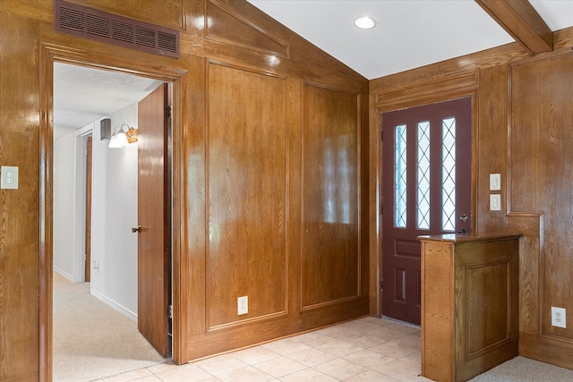 foyer entrance featuring wood walls, lofted ceiling, and light tile patterned floors