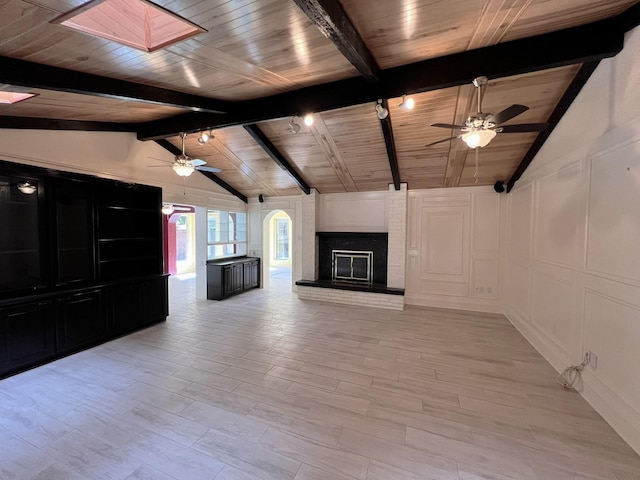 unfurnished living room featuring a fireplace, wooden ceiling, ceiling fan, and lofted ceiling with skylight