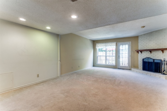 unfurnished living room with a fireplace, light colored carpet, and a textured ceiling