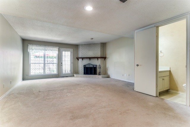 unfurnished living room with a fireplace, a textured ceiling, and light carpet