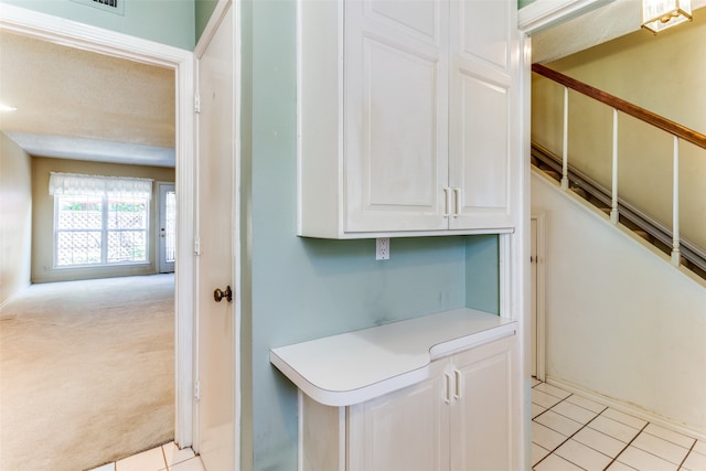 kitchen featuring white cabinets, light colored carpet, and a textured ceiling