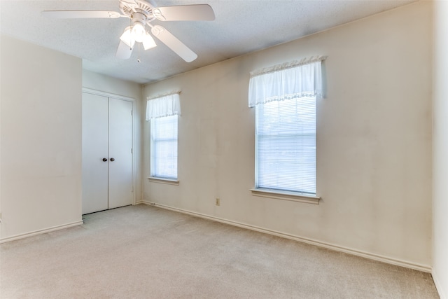 carpeted empty room featuring a textured ceiling and ceiling fan