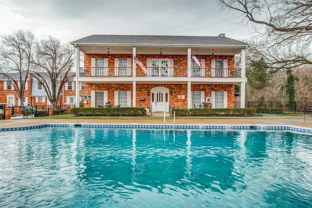 rear view of house featuring a balcony and a community pool