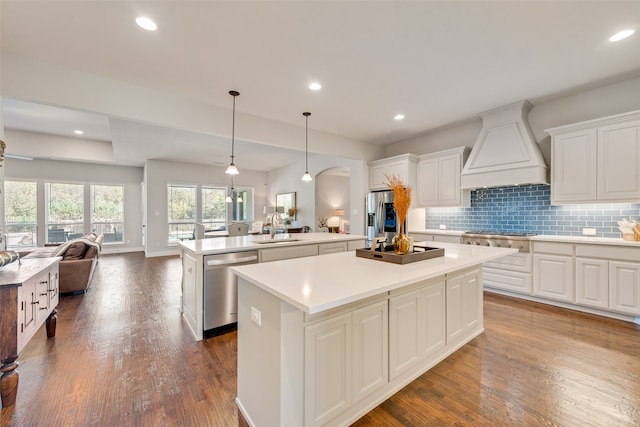 kitchen featuring premium range hood, appliances with stainless steel finishes, dark hardwood / wood-style floors, sink, and a center island