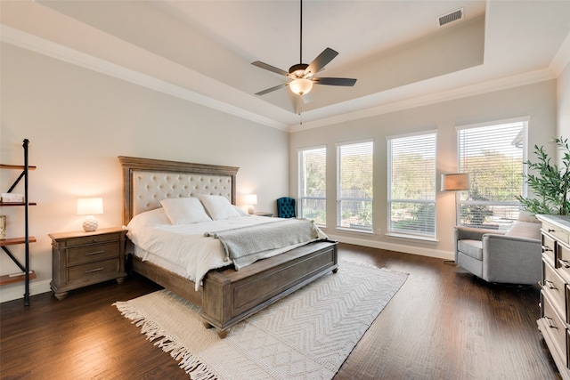 bedroom with ornamental molding, ceiling fan, dark hardwood / wood-style floors, and a tray ceiling