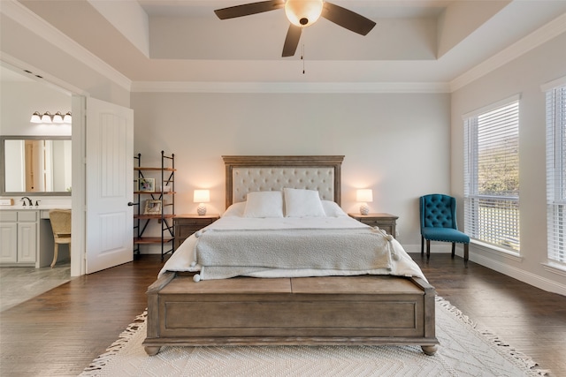 bedroom with ceiling fan, connected bathroom, dark hardwood / wood-style flooring, and a tray ceiling