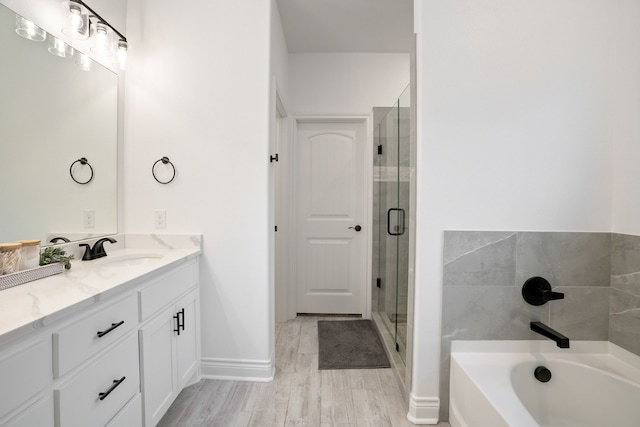 bathroom featuring wood-type flooring, plus walk in shower, and vanity