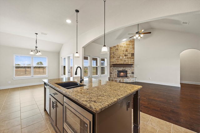 kitchen featuring appliances with stainless steel finishes, a wealth of natural light, a center island with sink, and light hardwood / wood-style flooring