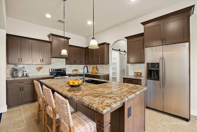 kitchen featuring a center island with sink, a barn door, tasteful backsplash, black range with electric stovetop, and stainless steel fridge