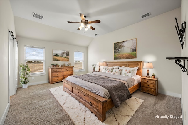 bedroom with a barn door, vaulted ceiling, light carpet, and ceiling fan