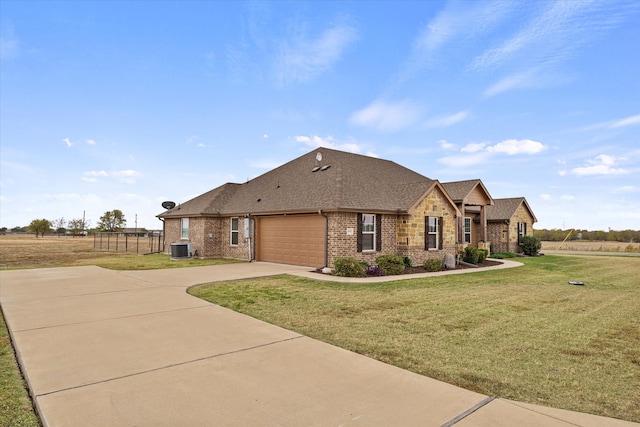 view of front facade with a garage, central AC, and a front yard