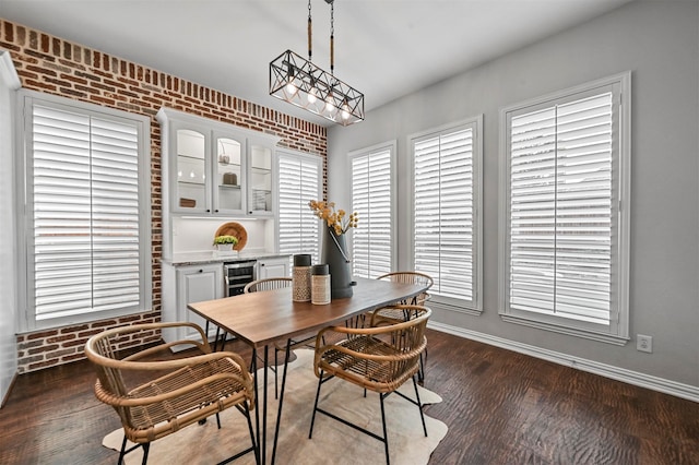 dining area featuring dark hardwood / wood-style flooring, brick wall, a notable chandelier, and wine cooler